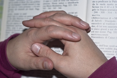 Hands in prayer of woman over the bible.