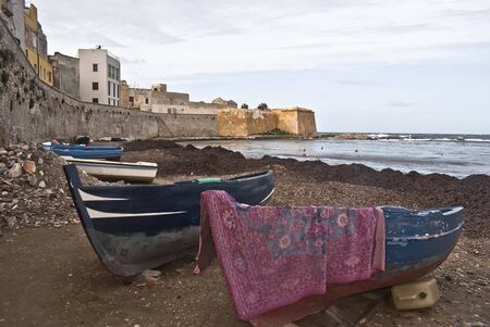 Boats in the marina of trapani with old buildings and sky cloudyの写真素材