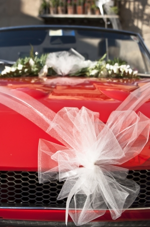 Red wedding car with white ribbon and flowers on the windshieldの写真素材