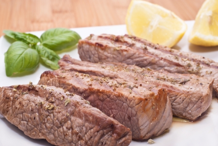 Grilled beef sliced with basil and lemonsの写真素材