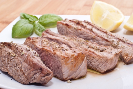 Grilled beef sliced with basil and lemonsの写真素材