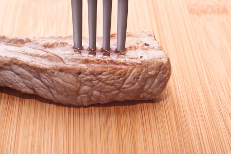 beef with fork on a wooden backgroundの写真素材