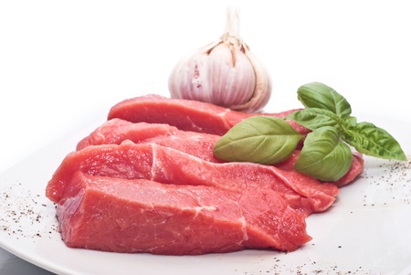 Raw beef on white background with basil and garlicの写真素材