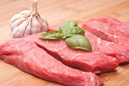 Raw beef on cutting board with basil and garlicの写真素材