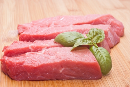 Raw beef on cutting board with basilの写真素材