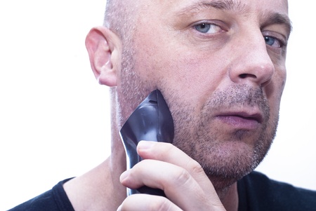 A closeup of a  man shaving his beard off with an electric shaver の写真素材