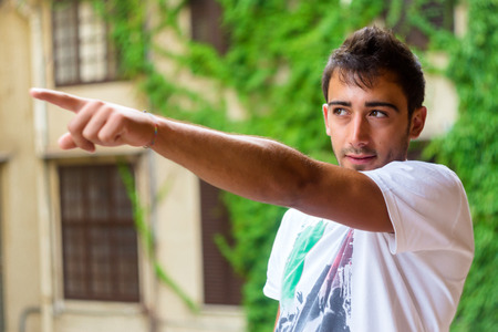 Young man pointing something against green natural backgroundの写真素材