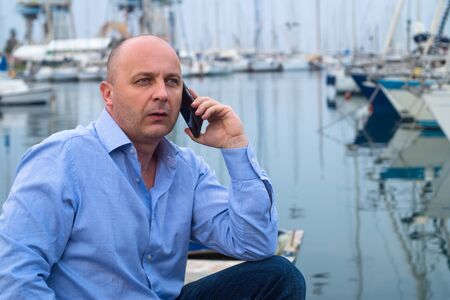 Businessman chatting on a mobile phone against harbour background