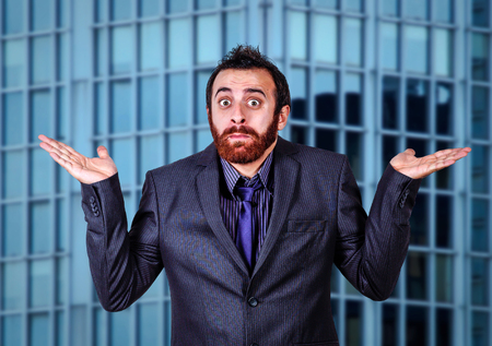 confused businessman doubting against blurred skyscraper backgroundの写真素材