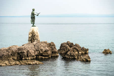 Opatija, Croatia - April 08, 2019: Famous Statue on rocks,  Maiden girl holding a seagull and facing the Adriatic Sea in Opatija, Croatiaのeditorial素材