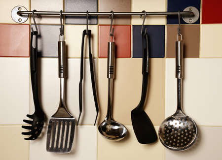 Kitchen utensils hanging on a colored  tile wallの写真素材