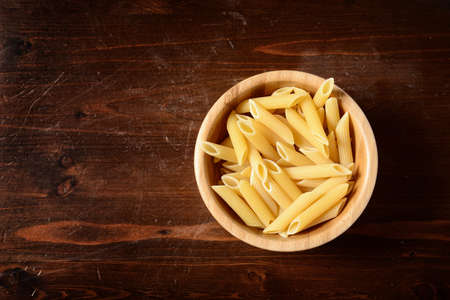pasta in a  wooden bowl on dark wooden tableの写真素材