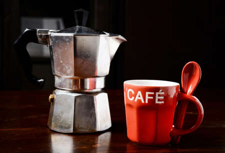 red coffee cup and  vintage coffeepot on dark wooden tableの写真素材
