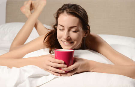 beautiful young woman in the bed with pink cup