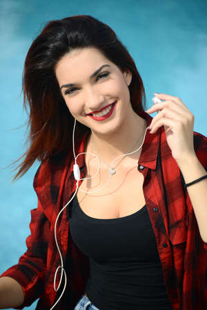 happy beautiful young woman relaxing  by the swimming pool with ear bud