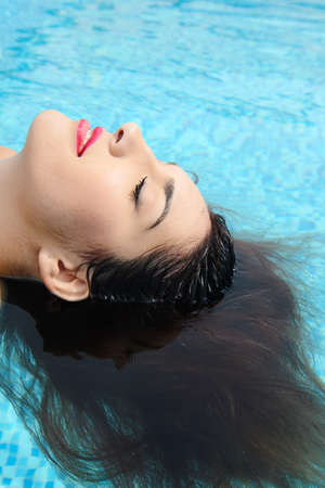 beautiful young woman relaxing in water by the swimming pool
