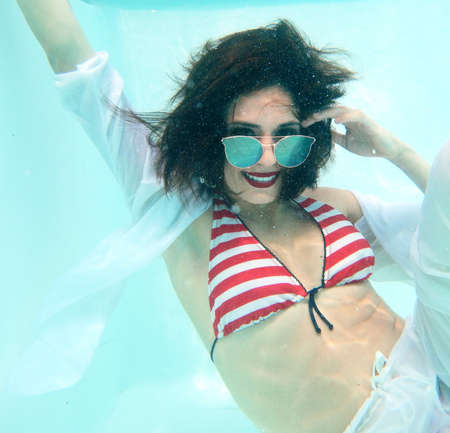 beautiful woman portrait underwater with sunglasses