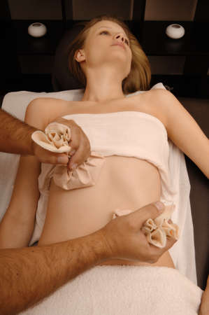 young woman receives body treatment in spa salonの写真素材