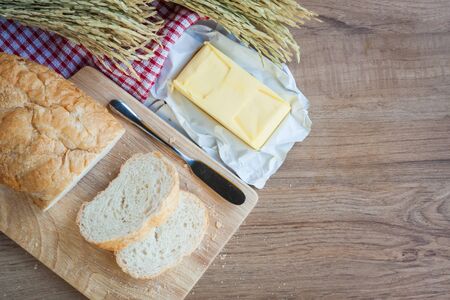 Sliced bread and butter on wood board with napery on wooden background
