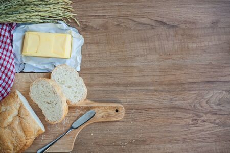 Sliced bread and butter on wood board with napery on wooden backgroundの写真素材