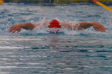 Swimmer in a swimming pool with a red cap on his headの写真素材