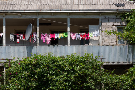 Clothes drying on clothesline in front of a house with green plantsの写真素材