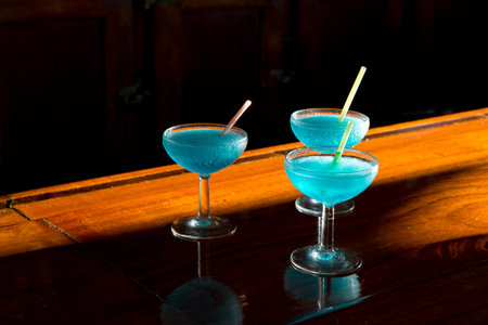 Blue CuraÃ§ao cocktails on a wooden table in a bar.の写真素材