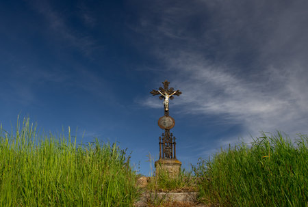 Cross on the hillside with grass and blue sky in the backgroundの写真素材