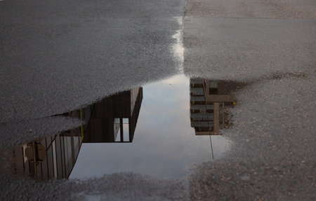 Reflection of a building in a puddle on the road.