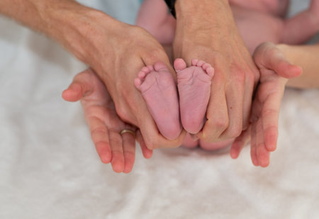 Newborn baby feet in the hands of a man and a womanの写真素材