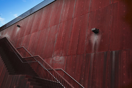 Red metal wall with stairs and metal railings in a modern cityの写真素材