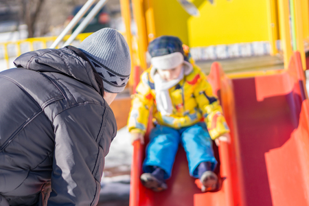 Outdoor father placing your child on slide. The child is in defocuses.の写真素材