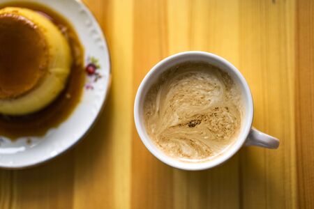 One white cups with aroma refreshing coffee on a kitchen table, cream witfh heart on the top. Top wieu, blured caramel cream on the left.の写真素材