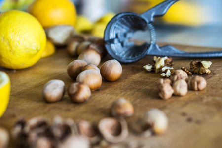 Closeup of whole and broken hazelnuts, lemon, walnut and nutcrackers on a wooden kitchen board. Health  concept.の写真素材