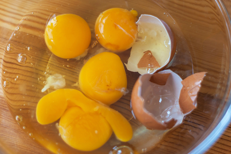 Closeup of broken eggs in transparent bowl.の写真素材