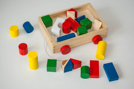 Children wooden trolley with colorful wooden cubes, cylinders and pyramids. Education concept.の写真素材