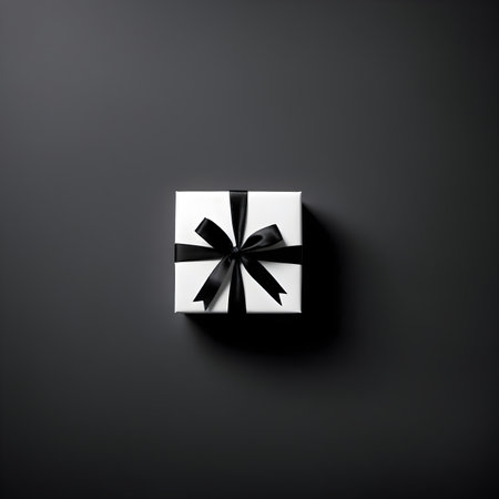 White gift box with black ribbon on black background. Top view.の素材