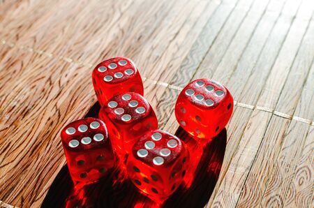 Red dice cubes with white points lying on the wicker wooden canvas background. Shallow depth of...