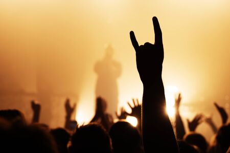 hand with a goat sign of dancing punk from the crowd at a rock concert of a popular band. silhouette...