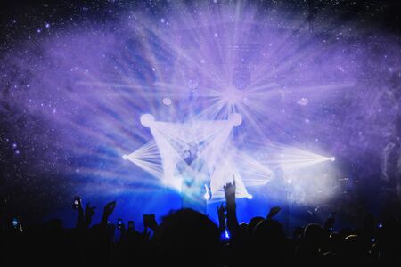 silhouette of musicians on the stage of the festival in the beautiful rays of a searchlight with a dancing crowd in the hall. music concert poster. night club atmosphereの写真素材