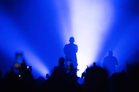 silhouette of musicians on stage in the light of a blue spotlight. atmosphere of a music festival with a dancing crowd. Blur. Selective focusの写真素材