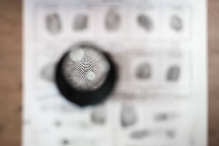 detailed black print in police report through a magnifying glass. investigation of a crime. Forensic-medical examination. detective agency.の写真素材