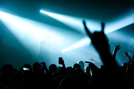 blurred horns gesture from the crowd at a concert. full hall at a rock concert. atmosphere of a music festival.の写真素材