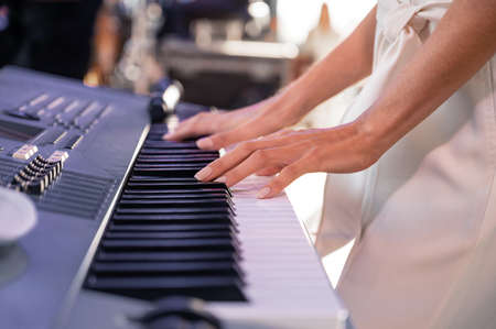 Female hands on the keys of a piano synthesizer. Musician playingの写真素材