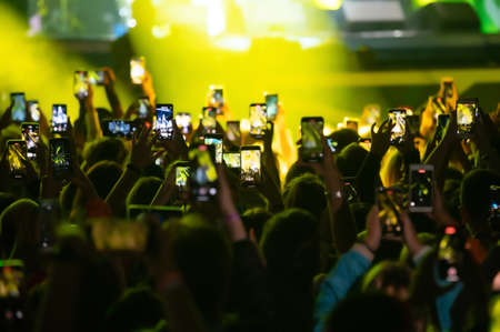 The crowd at the concert is filming the event on the phoneの写真素材