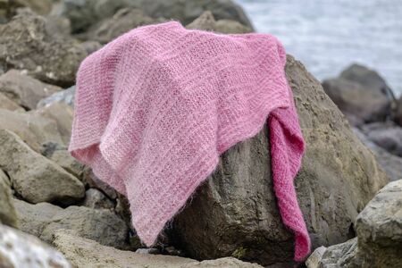 Knitted magenta scarf on a stone on the beach 2の写真素材
