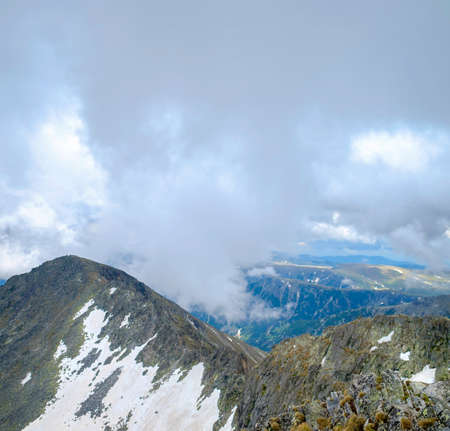 Snow-Capped Mountain Peaks with Mystic Foggy Cloudsの写真素材