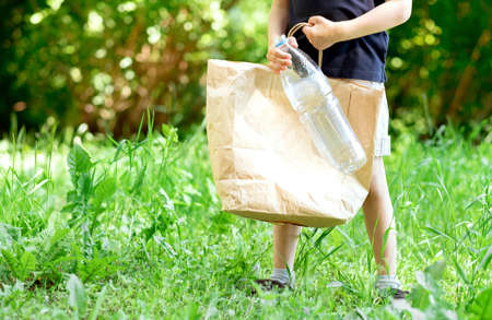 The boy on the street collects plastic in a bag. Sorting garbage. Protecting the environment from an early age. The problem of ecology in the world. plastic problem.の写真素材