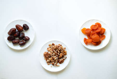 dates, dried apricots, walnuts on a white background. Useful candies without sugar. Ingredients for healthy sweets. Isolate with wholesome food.の写真素材