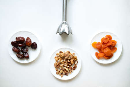 dates, dried apricots, walnuts, blender on a white background. Useful candies without sugar. Ingredients for healthy sweets. Isolate with wholesome foodの写真素材